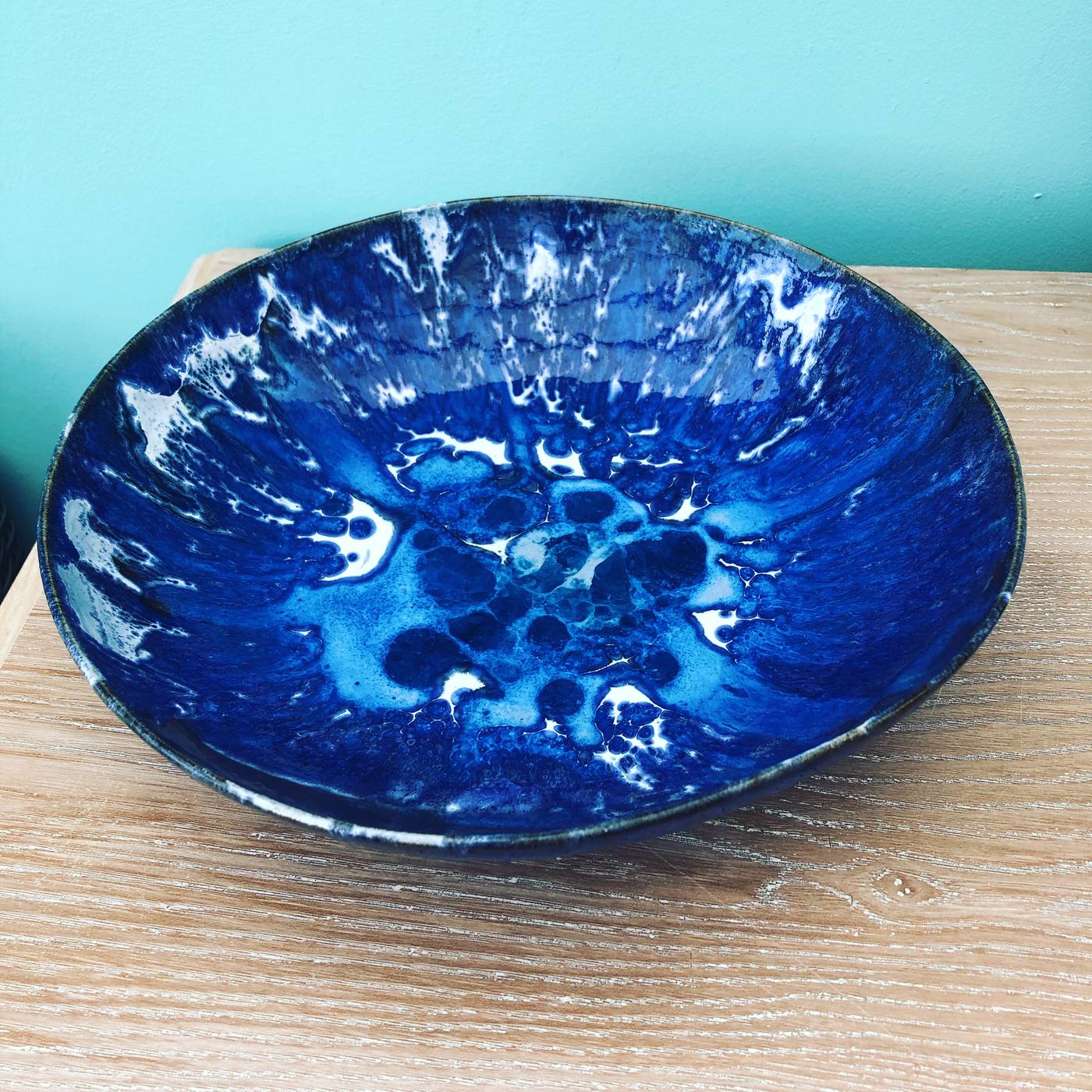 Blue crystalline glaze bowl against a teal wall